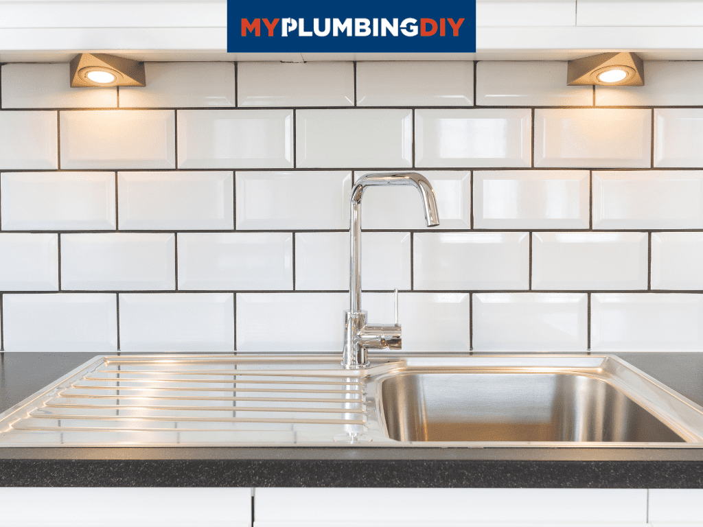 stainless steel sink in white tile kitchen